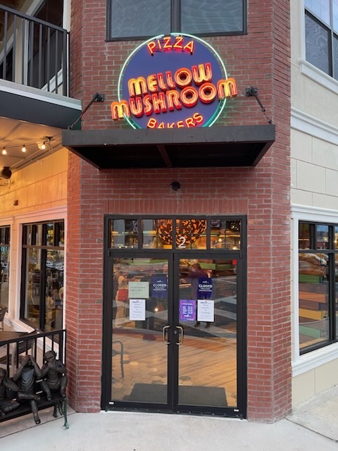 A brick store facade with a Mellow Mushroom neon sign.
