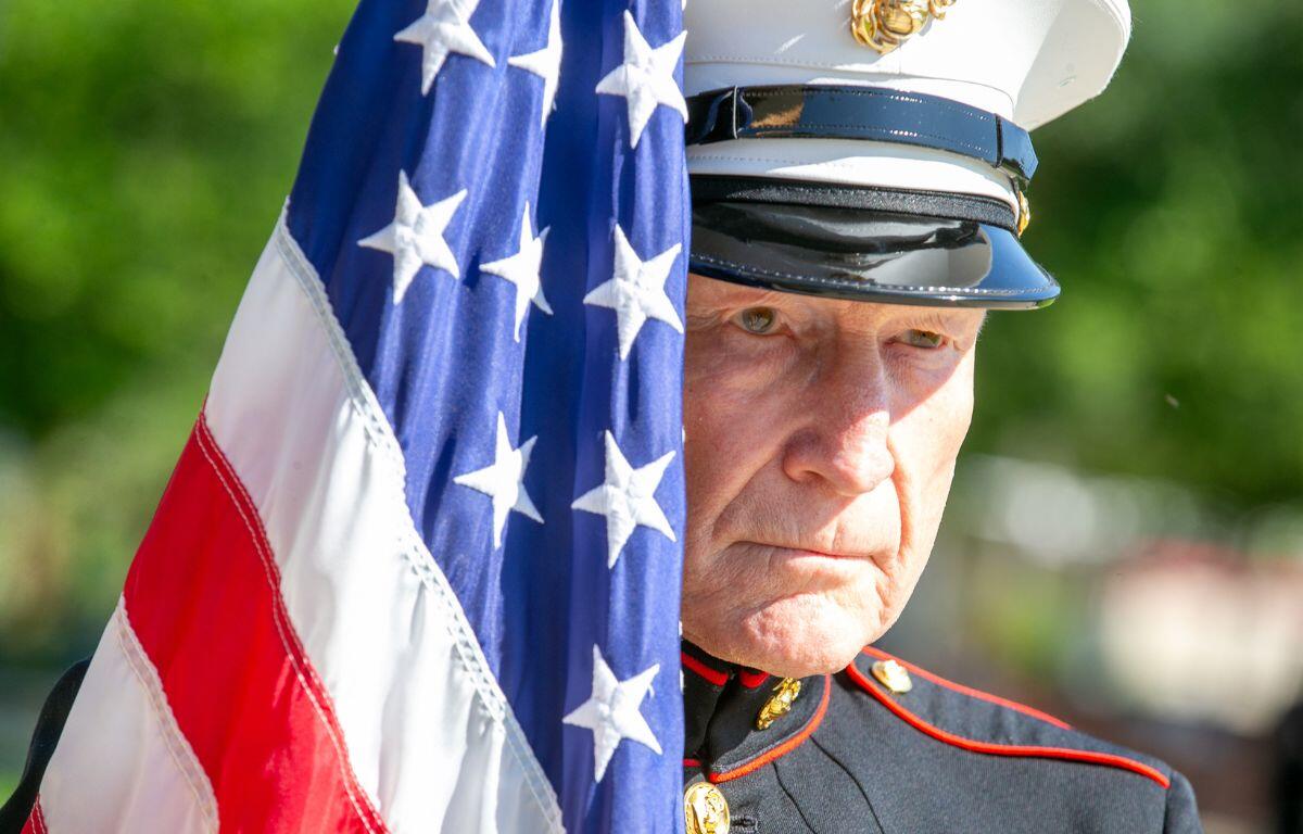 USMC veteran Sgt. Bob Levenson standing beside an American flag at Ocala’s 2024 Memorial Day ceremony.