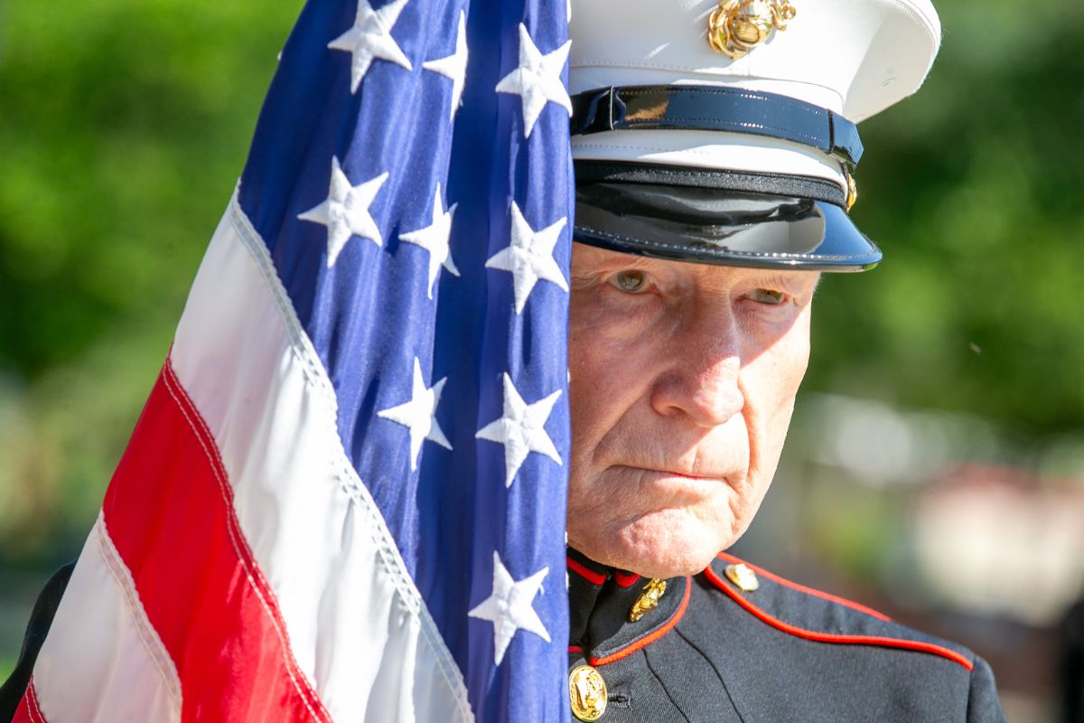 USMC veteran Sgt. Bob Levenson standing beside an American flag at Ocala’s 2024 Memorial Day ceremony.