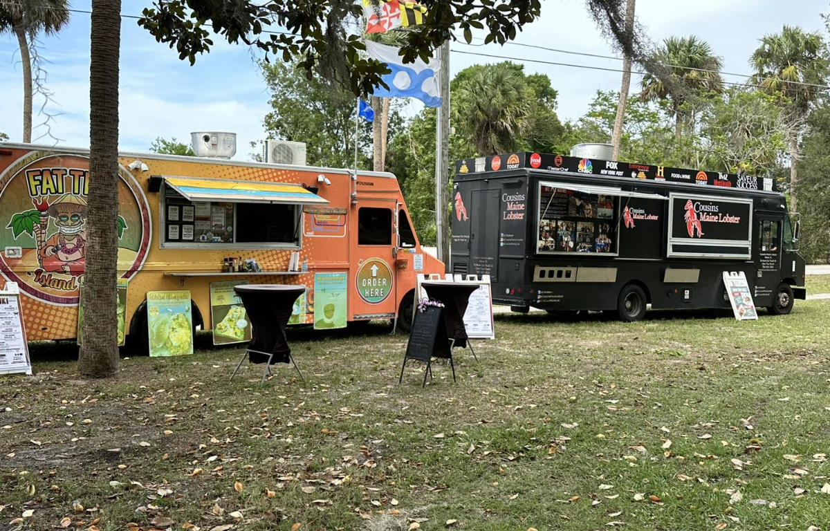 Two food trucks set up on the grass at Lake Lillian Park in Belleview, ready to serve guests at the Friday Foodie Fest.