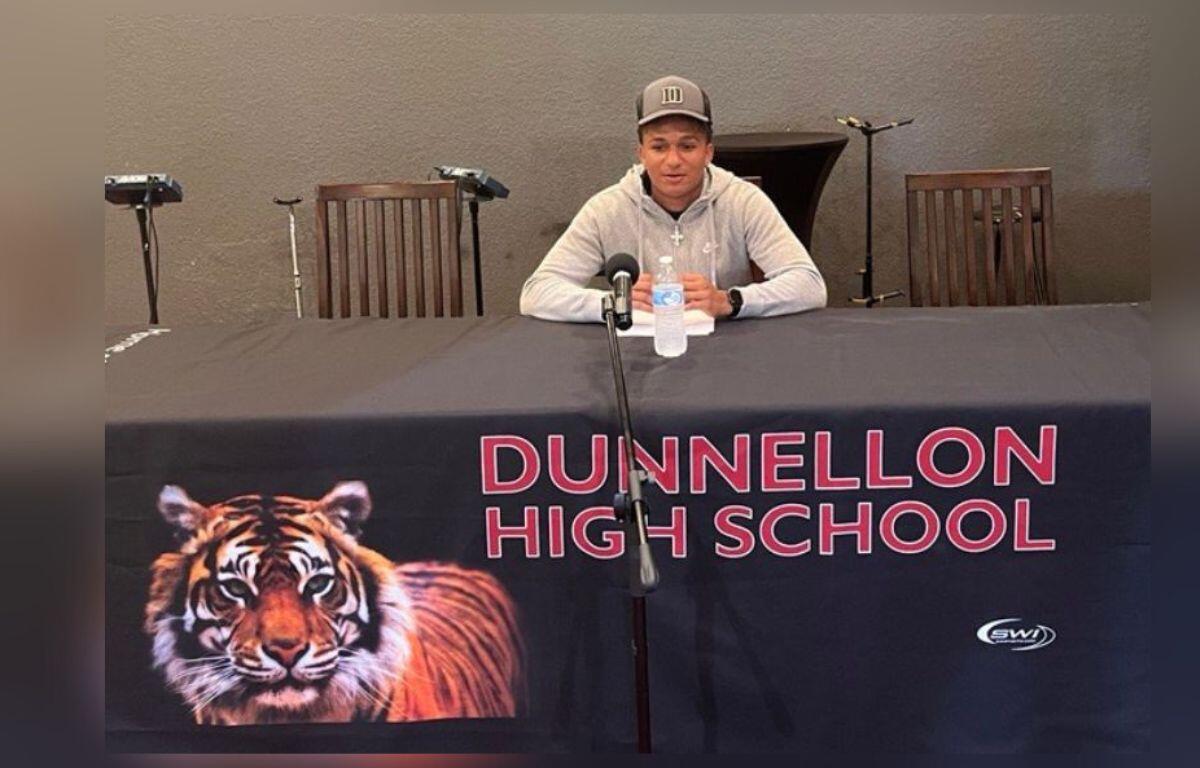 Image shows Dunnellon High senior seated in front of a long table as he prepared to sign his letter of intent to play fooball for Eastern Michigan University.