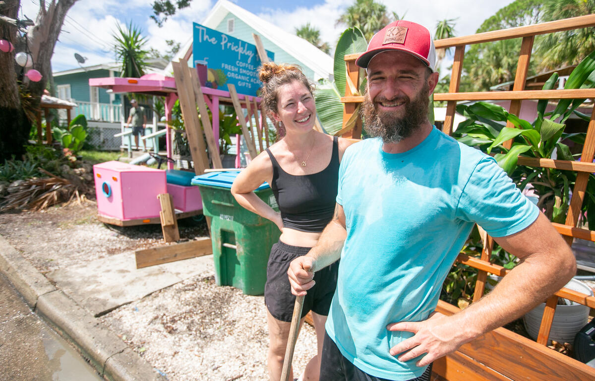 Image shows Hanna Healey (left) and Beau Hoffmann (right) cleaning up outside The Prickly Palm Cafe in Cedar Key, FL,