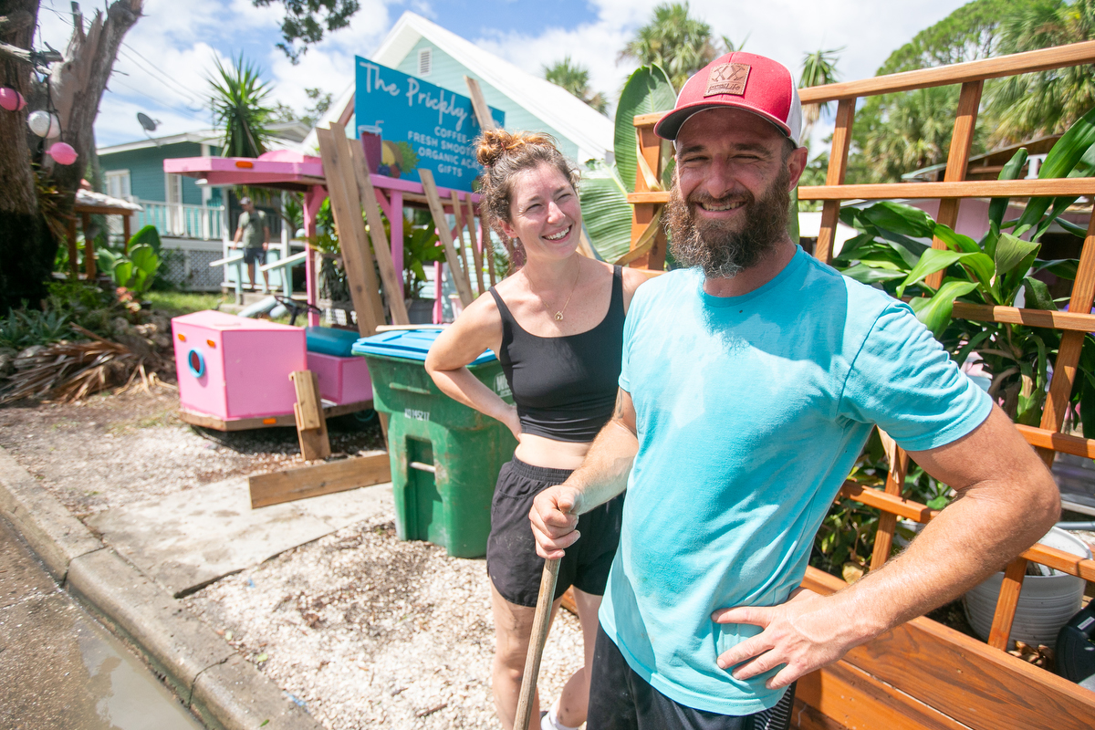 Image shows Hanna Healey (left) and Beau Hoffmann (right) cleaning up outside The Prickly Palm Cafe in Cedar Key, FL,