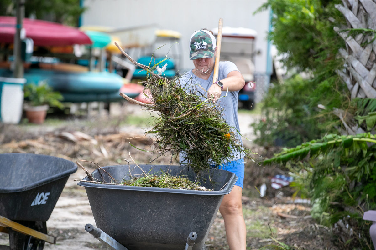 Vanessa Bastow is seen picking up debris and putting it in a wheelbarrow around the Faraway Inn in Cedar Key, FL, following Hurricane Debby.