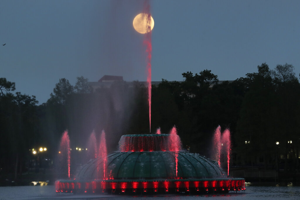 The supermoon rises in the sky in front of a fountain at Lake Eola in Orlando.