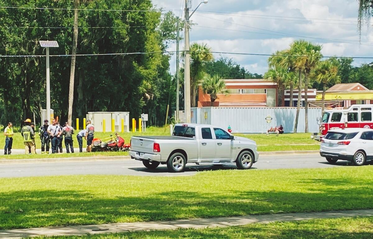 A silver truck sits near the median while first responders assist a downed motorcyclist near the Silver Springs Walmart in Ocala.
