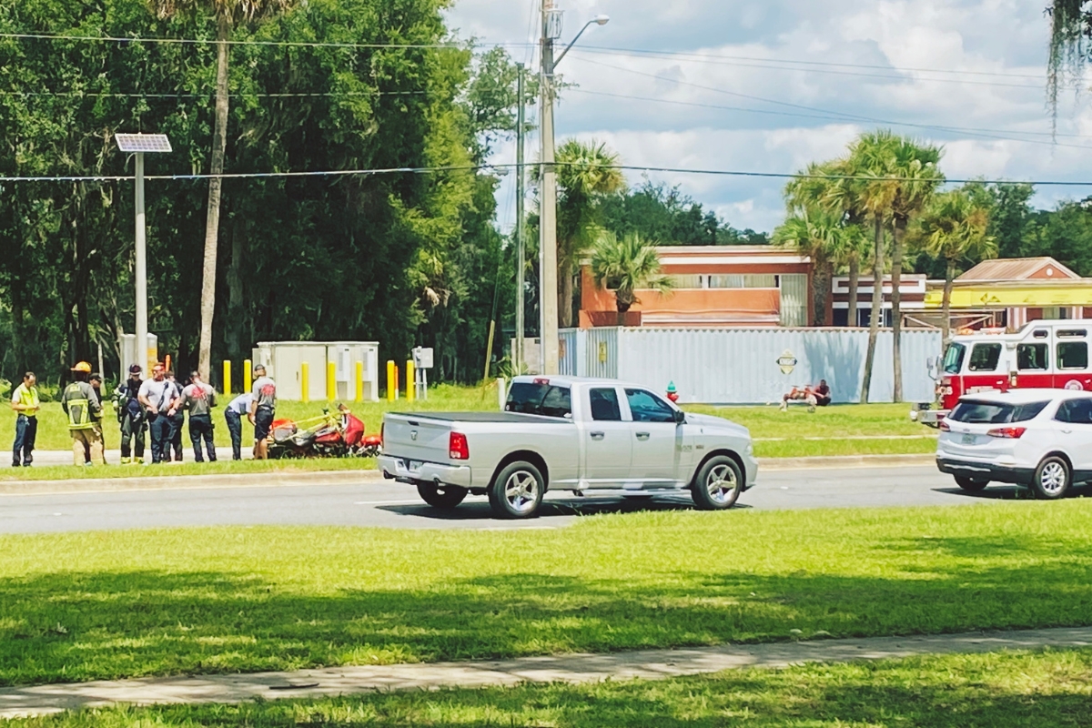 A silver truck sits near the median while first responders assist a downed motorcyclist near the Silver Springs Walmart in Ocala.