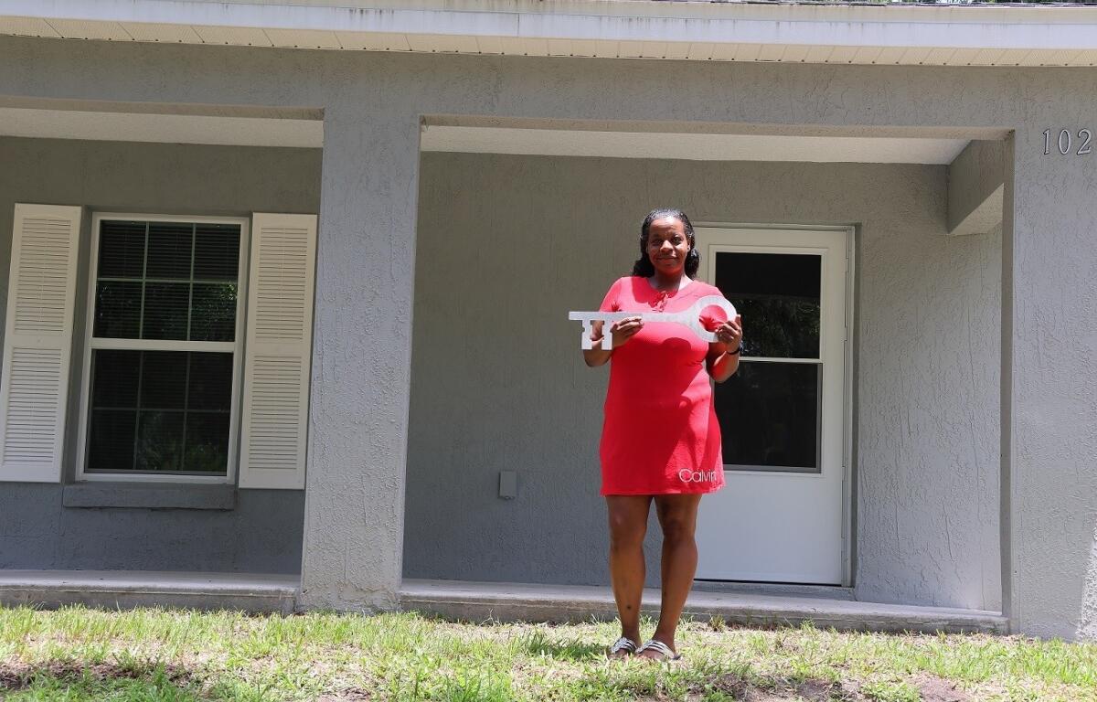 Nicole Duncan stands in front of her home with a giant key. Sumter County, FL