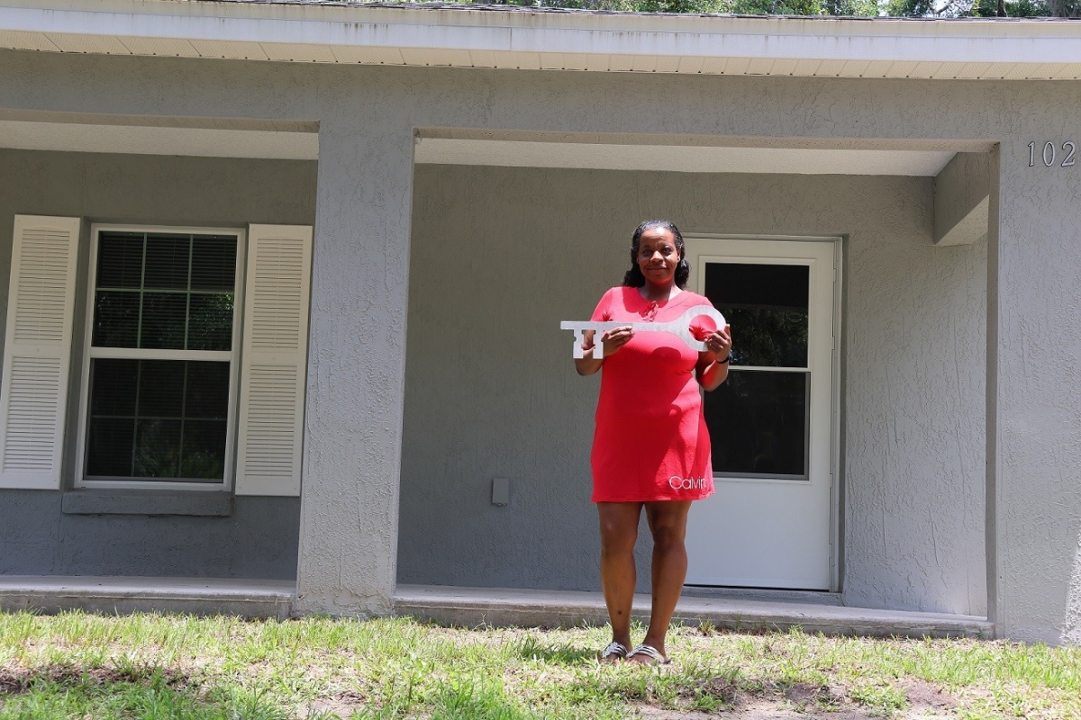 Nicole Duncan stands in front of her home with a giant key. Sumter County, FL