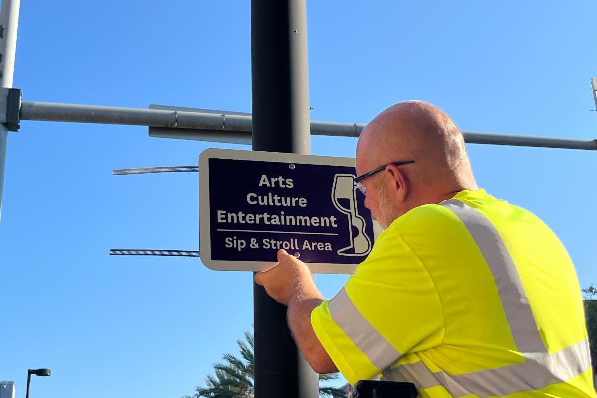 Gainesville city worker installs a sign on a poll denoting the Arts Culture Entertainment district where people can have open containers of alcohol.