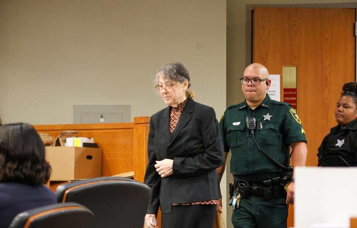 A Marion County deputy walks behind Susan Lorincz at the Marion County Courthouse in Ocala.