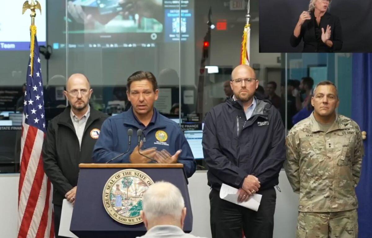 Image shows Florida Gov. Ron DeSantis flanked by State Emergency Management Director Kevin Guthrie and Florida Department of Transportation Secretary Jared Perdue, and Florida National Guard Maj. Gen. John Haas.