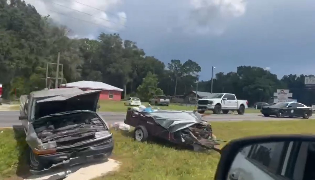 Image shows a damaged pick-up truck in the median of Highway 441 with a utility trailer by its side.