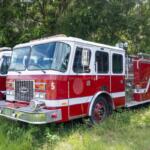 Marion County fire engine parked in grass near wooded area