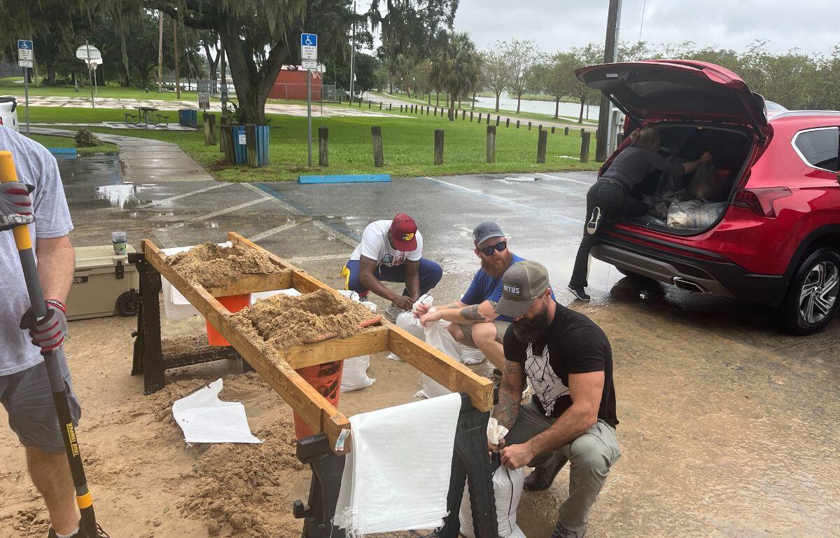 People fill sandbags and load them into a red SUV at a Marion County distribution site ahead of an expected storm.