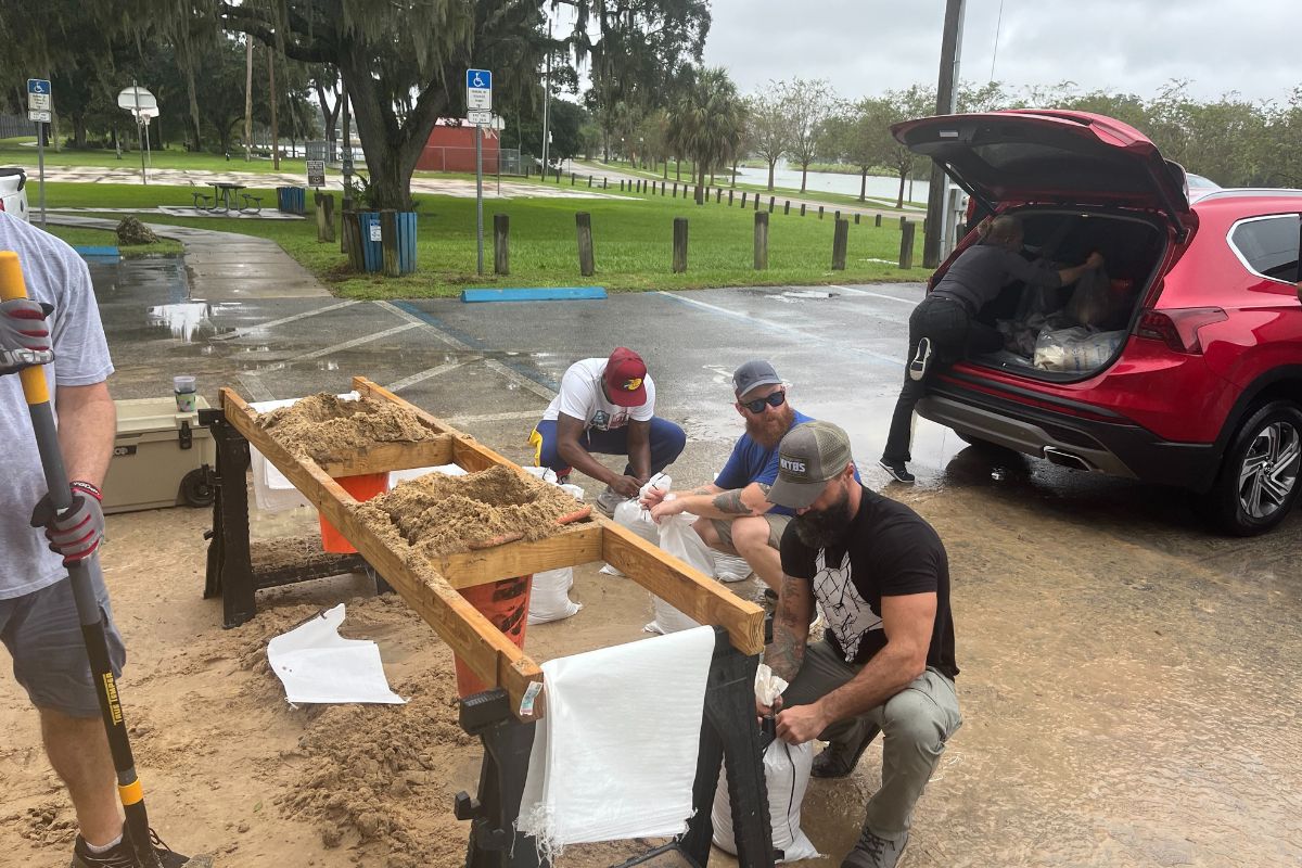People fill sandbags and load them into a red SUV at a Marion County distribution site ahead of an expected storm.