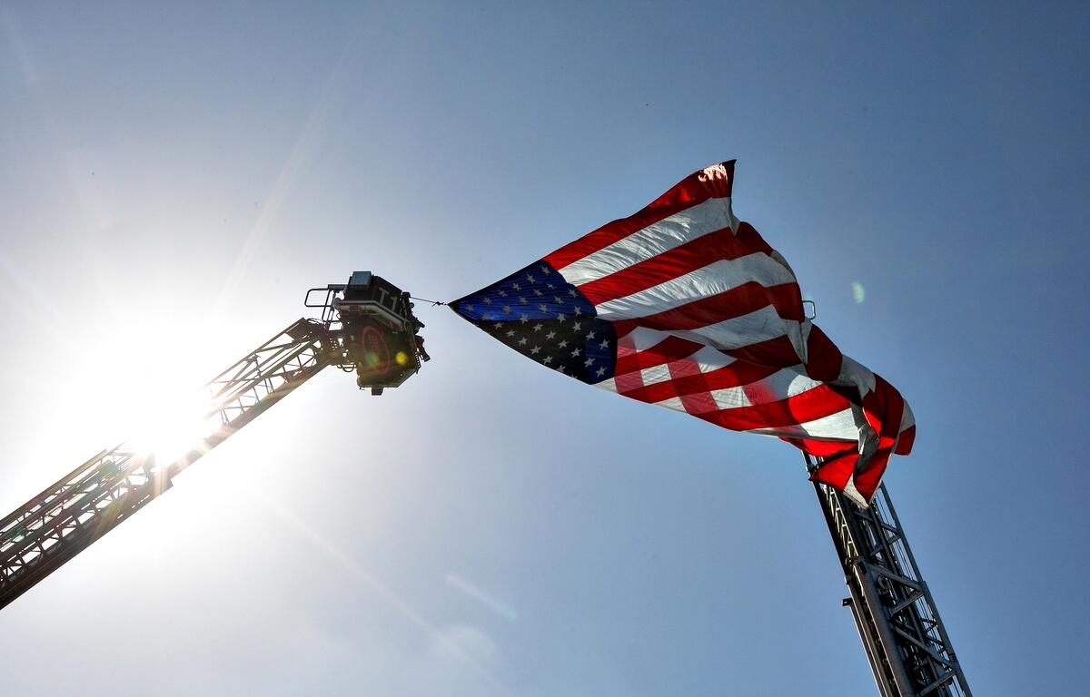 Flag flying between ladders in sunshine blue sky