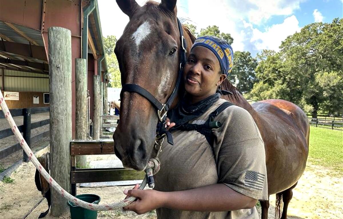 Kira Zeynalov, a U.S. Navy veteran managing PTSD and MS, shares a tender moment with Rowdy, one of the therapy horses at the Marion Therapeutic Riding Association in Ocala.