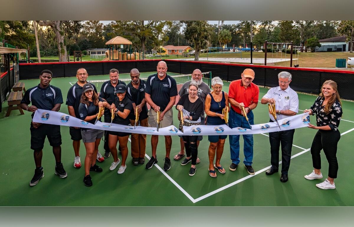 Photo of Marion County Commissioner Craig Curry and others getting ready to cut a white ribbon at the new Silver Springs Shores pickleball court.