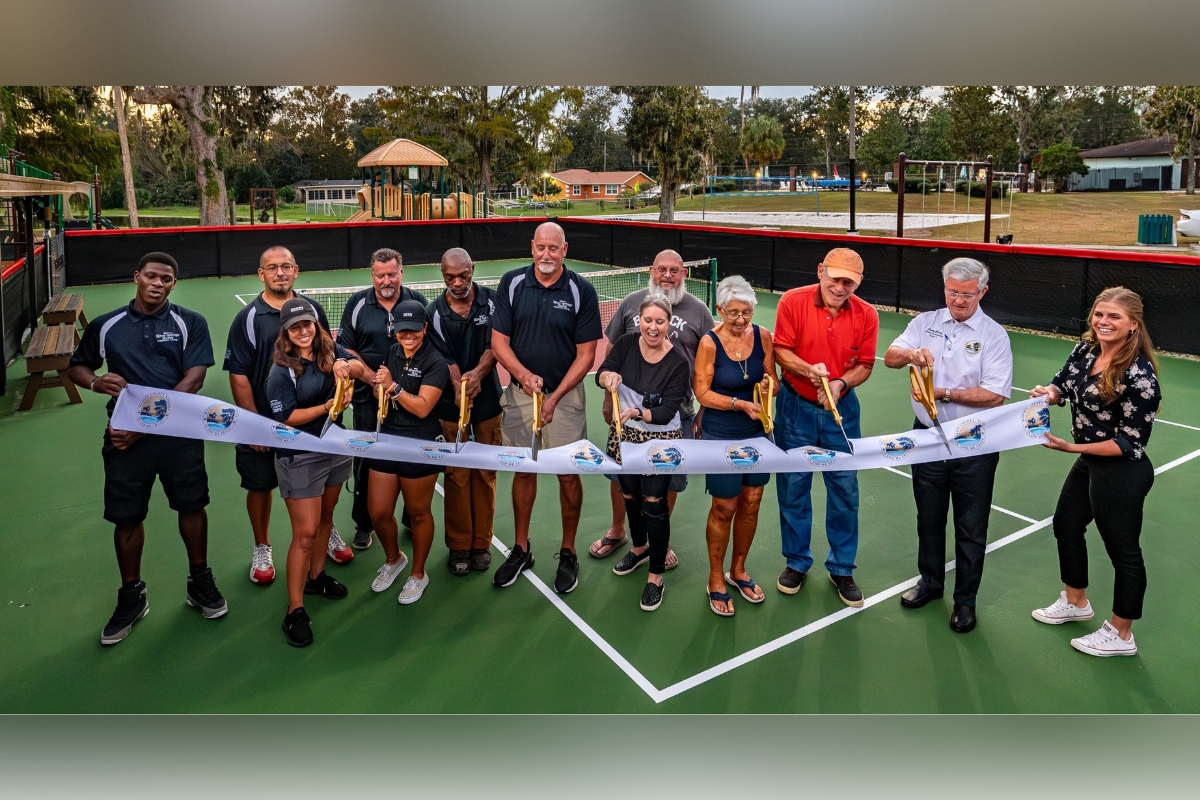 Photo of Marion County Commissioner Craig Curry and others getting ready to cut a white ribbon at the new Silver Springs Shores pickleball court.