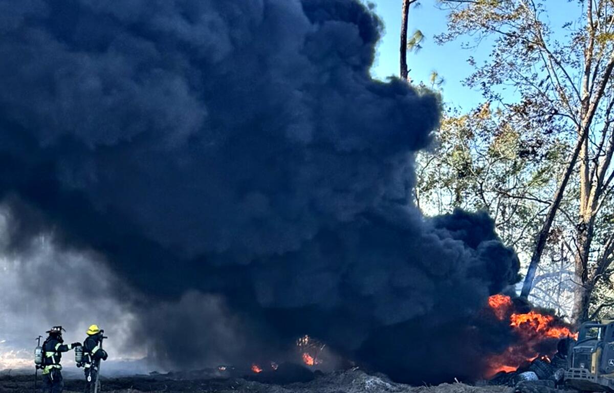 Smoke fills the air as firefighters extinguish a large fire involving tires and nearby trees in Citra on Dec. 2.