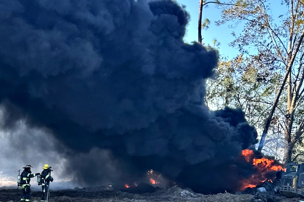 Smoke fills the air as firefighters extinguish a large fire involving tires and nearby trees in Citra on Dec. 2.