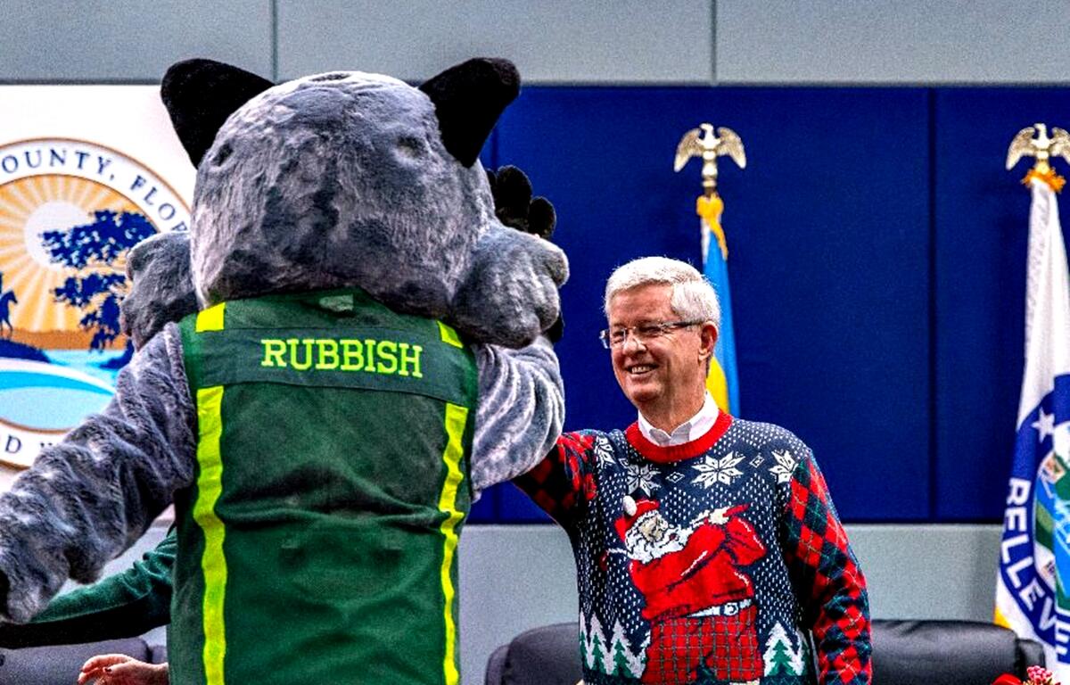 Rubbish the raccoon gives County Commissioner Craig Curry a high five during the recognition of a major anti-littering case and new business partners.