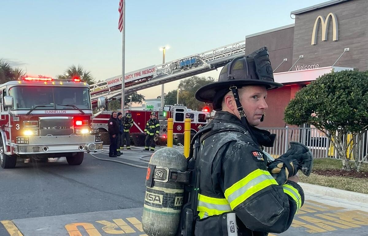 A smoke alarm sounds, alerting occupants to potential danger, as firefighters respond to a commercial structure fire in Dunnellon, Florida.