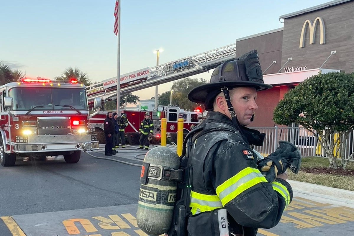 A smoke alarm sounds, alerting occupants to potential danger, as firefighters respond to a commercial structure fire in Dunnellon, Florida.