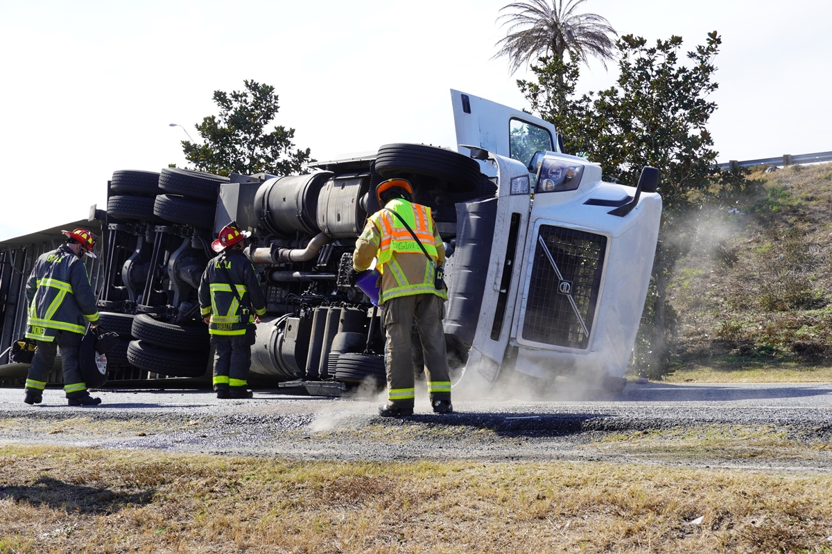 A produce-filled semi-truck lies on its side after crashing near Exit 354, prompting road closures and hazardous material cleanup.