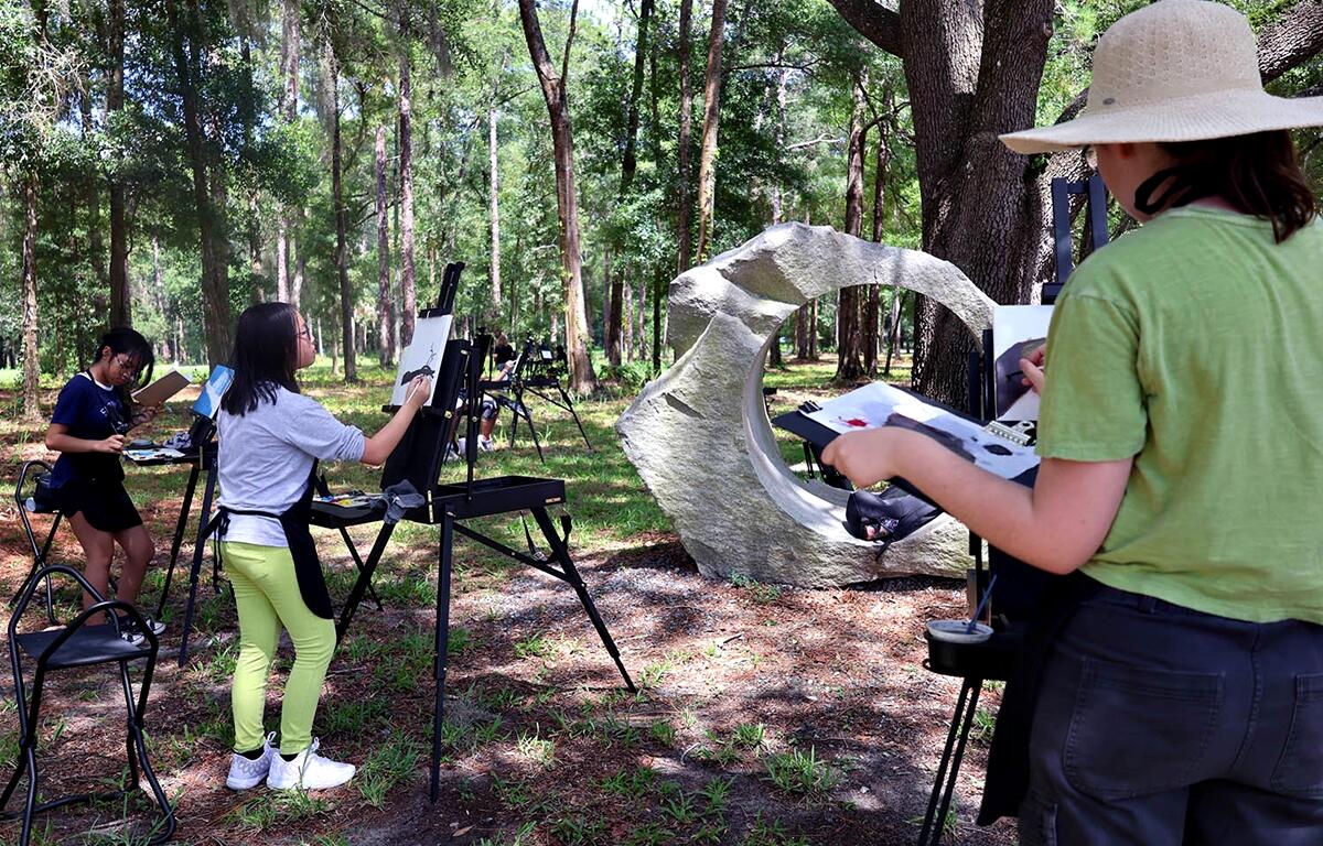 Campers at the Appleton Museum of Art’s Summer Art Camp paint outdoors during an en plein air session, capturing nature’s beauty on canvas.