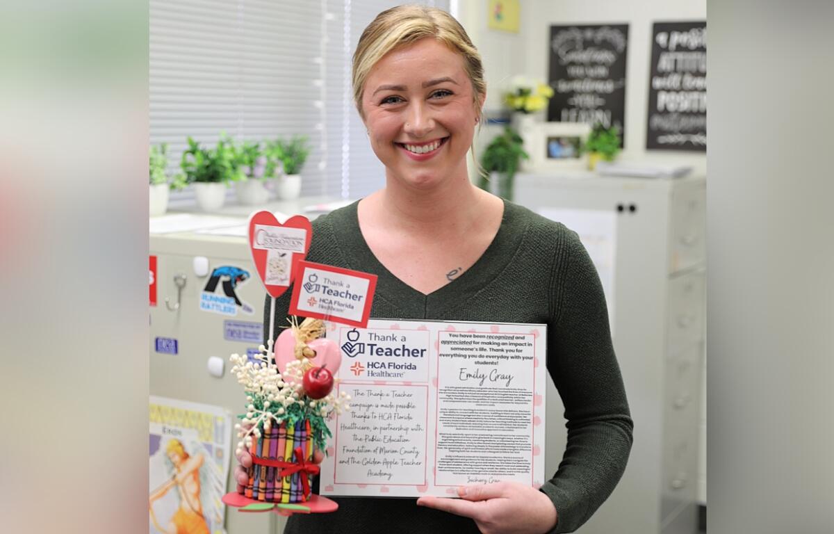 Emily Gray, an AICE English Literature teacher at Belleview High School, smiles while holding her "Thank a Teacher" award during a recognition event on Feb. 27, 2024. The award, presented by HCA Florida Ocala Hospital and the Public Education Foundation of Marion County, honors outstanding educators in the community.