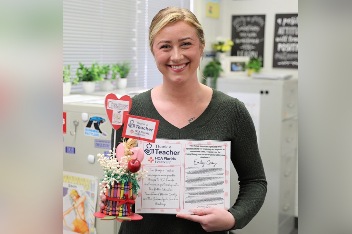 Emily Gray, an AICE English Literature teacher at Belleview High School, smiles while holding her "Thank a Teacher" award during a recognition event on Feb. 27, 2024. The award, presented by HCA Florida Ocala Hospital and the Public Education Foundation of Marion County, honors outstanding educators in the community.
