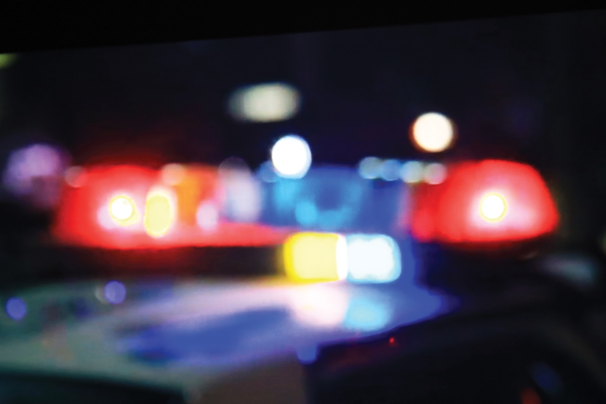 Blurred red and blue police lights glowing in the dark during a nighttime emergency response.