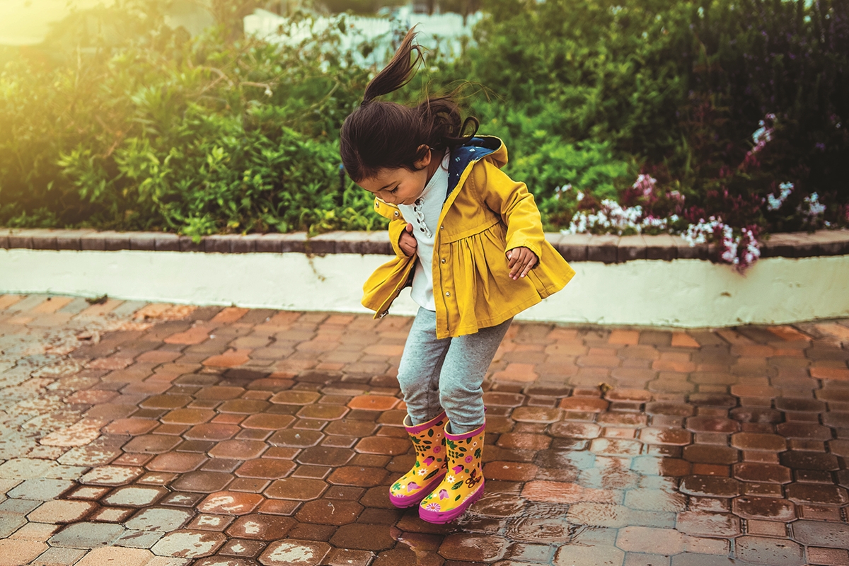 A child enjoys splashing in puddles as rainy skies begin to clear, signaling improving weather conditions for the remainder of the week.