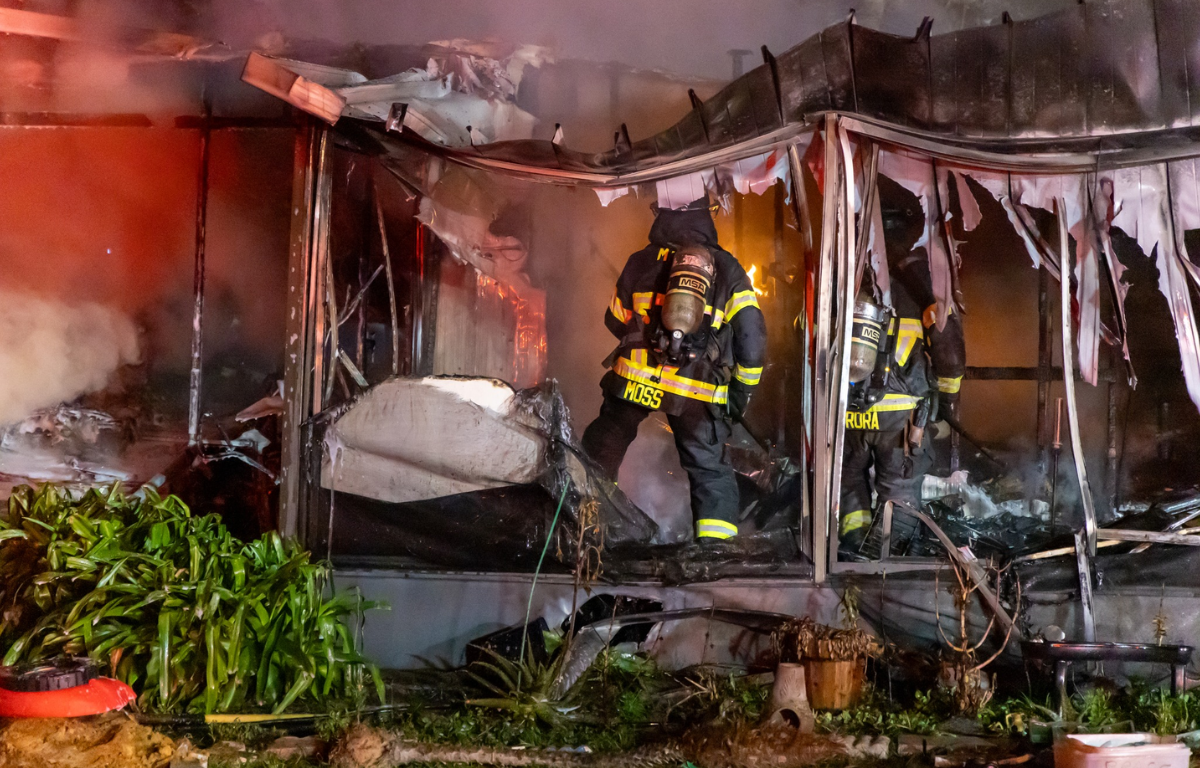 Firefighters climb into the badly burnt mobile home to extinguish what's left of the fire.