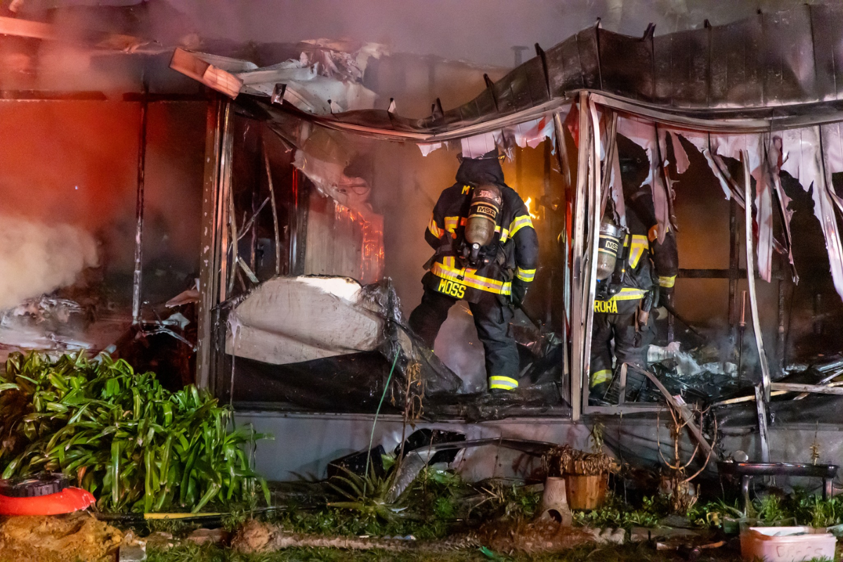 Firefighters climb into the badly burnt mobile home to extinguish what's left of the fire.