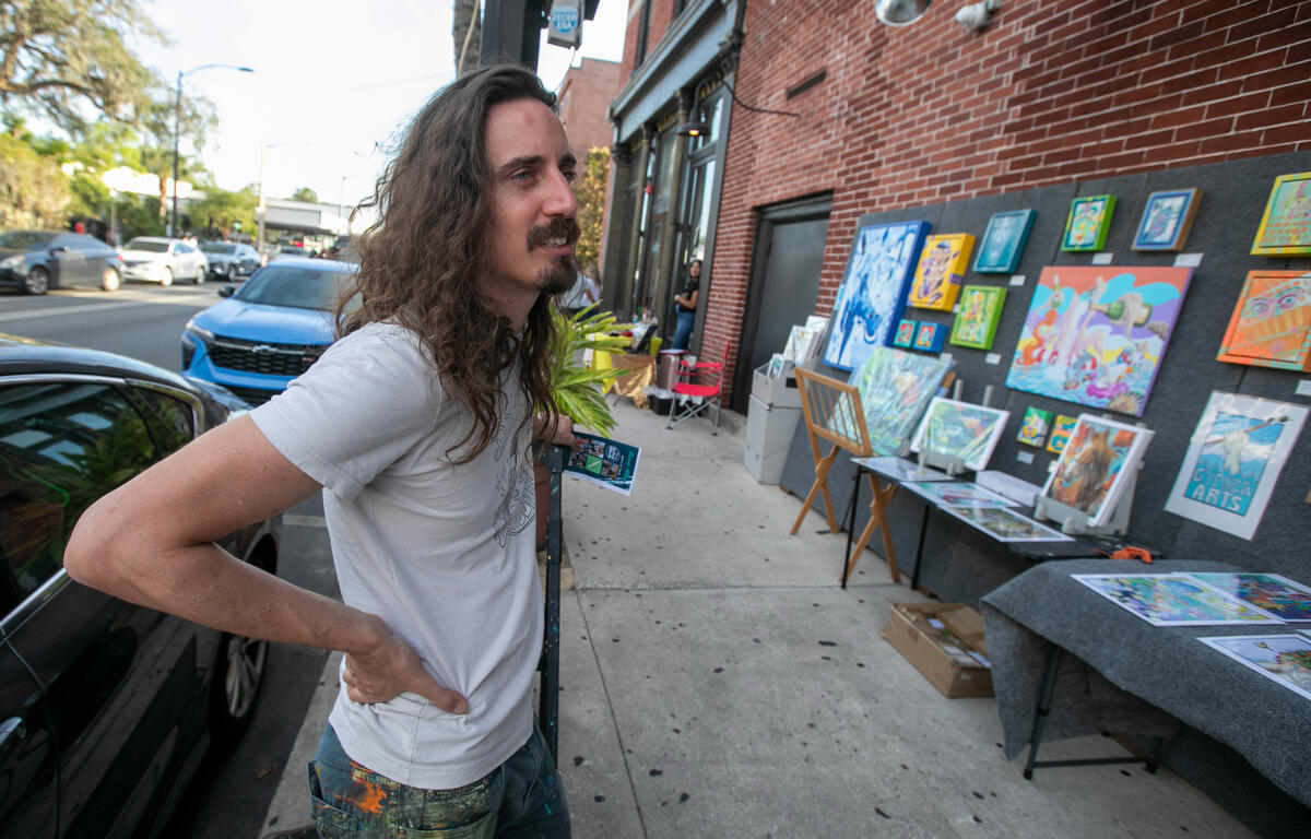 Artist Justin Alsedek waits for visitors to his art downtown during First Friday Art Walk in Ocala, FL on