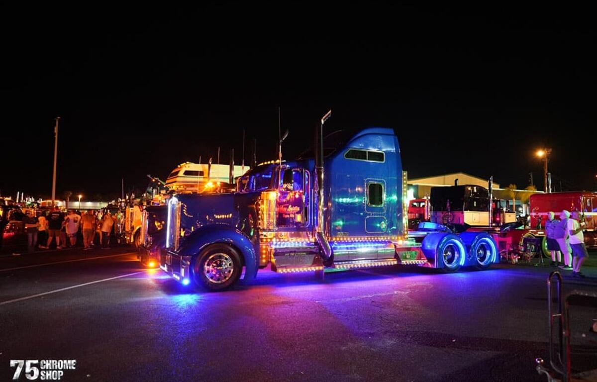 A custom big rig glows under neon lights during the Friday night light show at the 2024 75 Chrome Shop Truck Show in Wildwood.