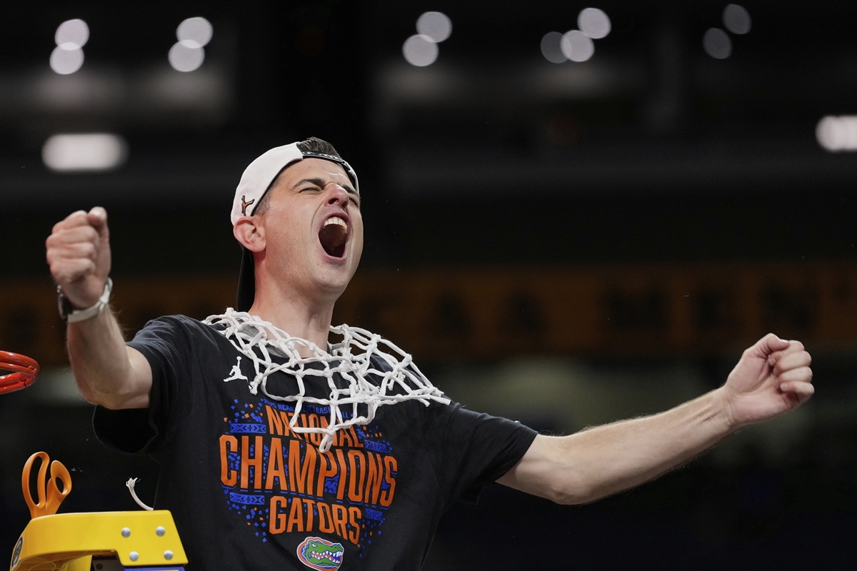 Florida Gators head coach Todd Golden celebrates after winning the national championship, wearing a "National Champions" T-shirt and a cut basketball net draped around his neck.