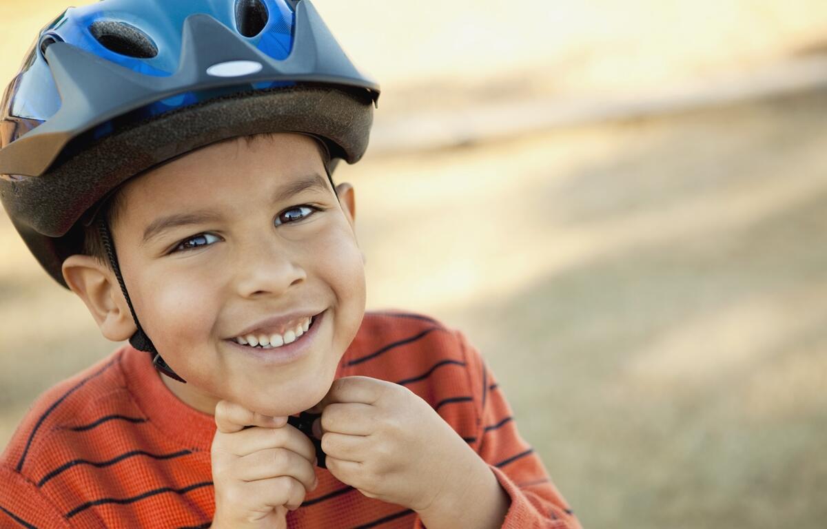 Little boy putting on his helmet.