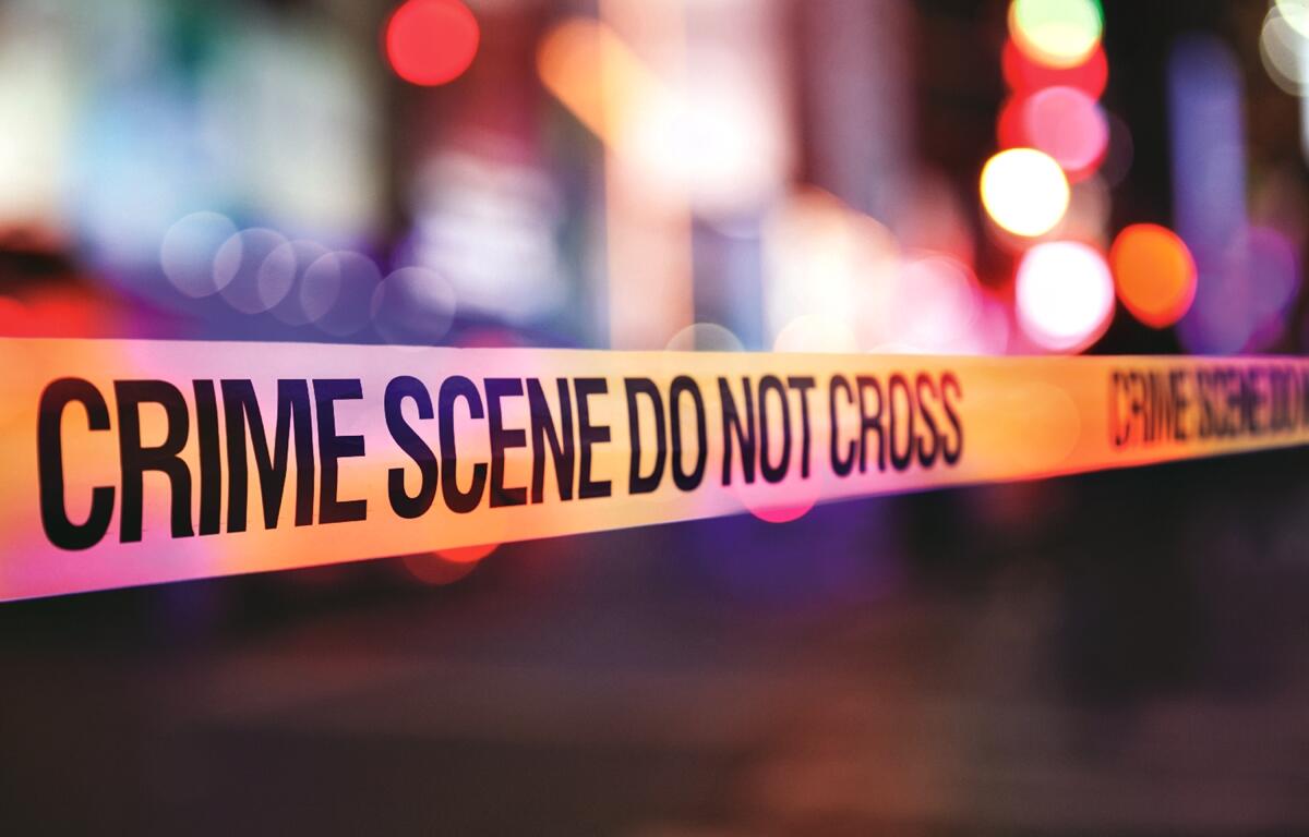 Yellow crime scene tape with blurred police lights in the background