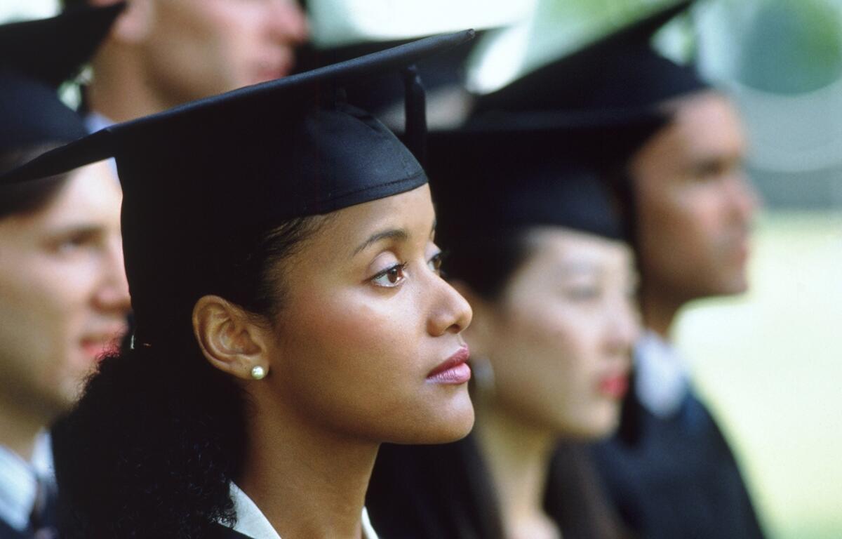 High school seniors in caps and gowns wait to graduate.