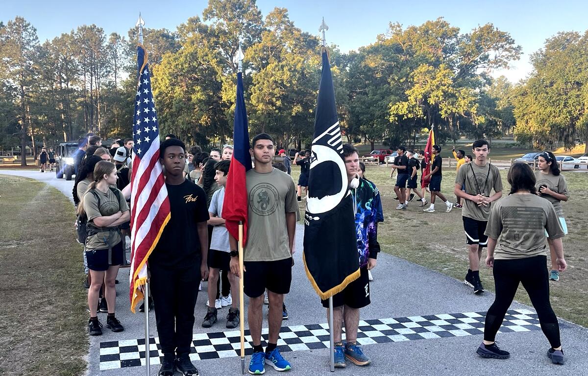 JROTC cadets stand at the starting line with U.S., Texas, and POW-MIA flags before the 15-mile Bataan Memorial March at Baseline Trailhead on April 18, 2025.