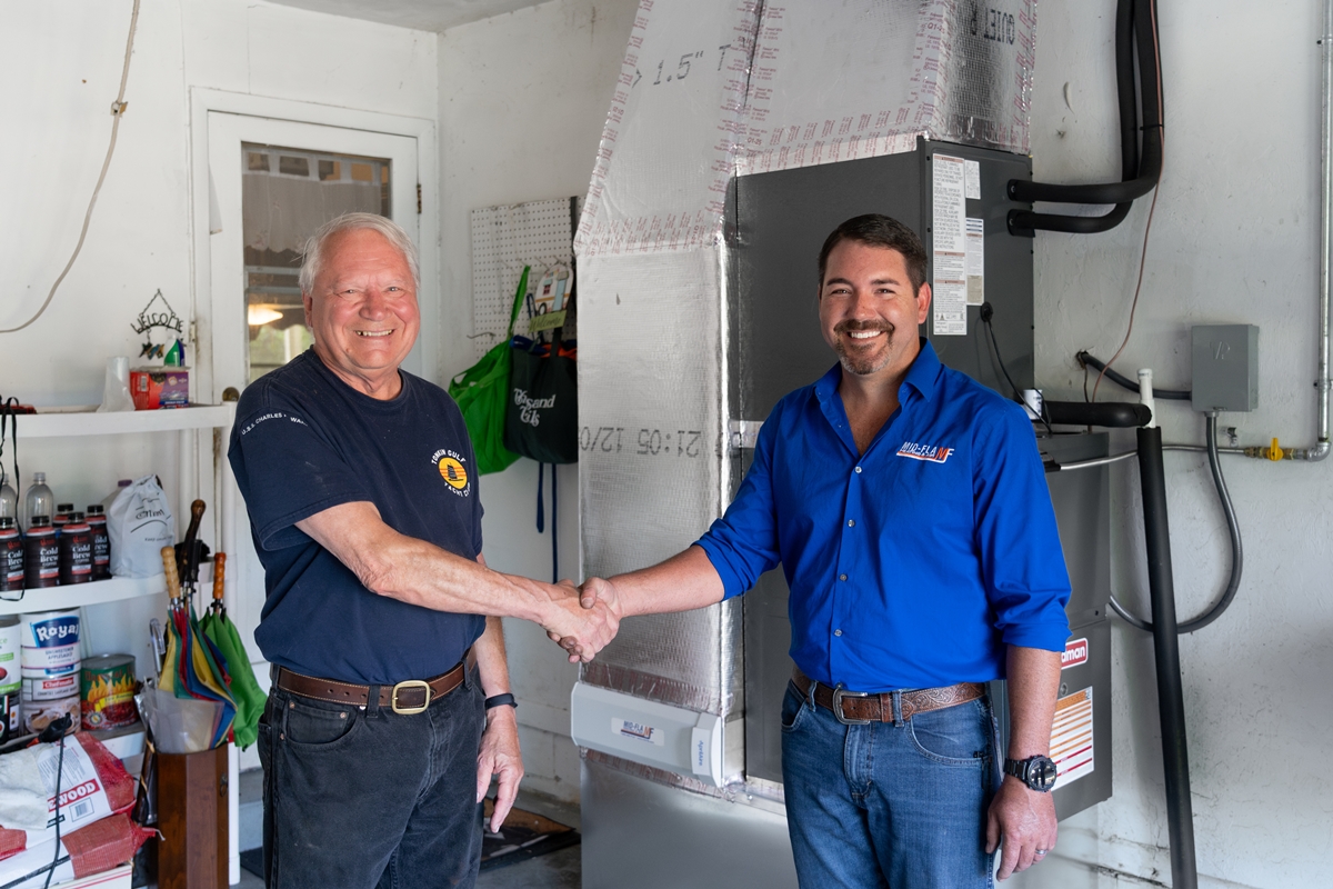 Robert Monk, left, shakes hands with Mid Florida Heating & Air Regional VP Travis Lyons after receiving a new HVAC system through the company’s Ugliest AC makeover contest in Gainesville, Fla.