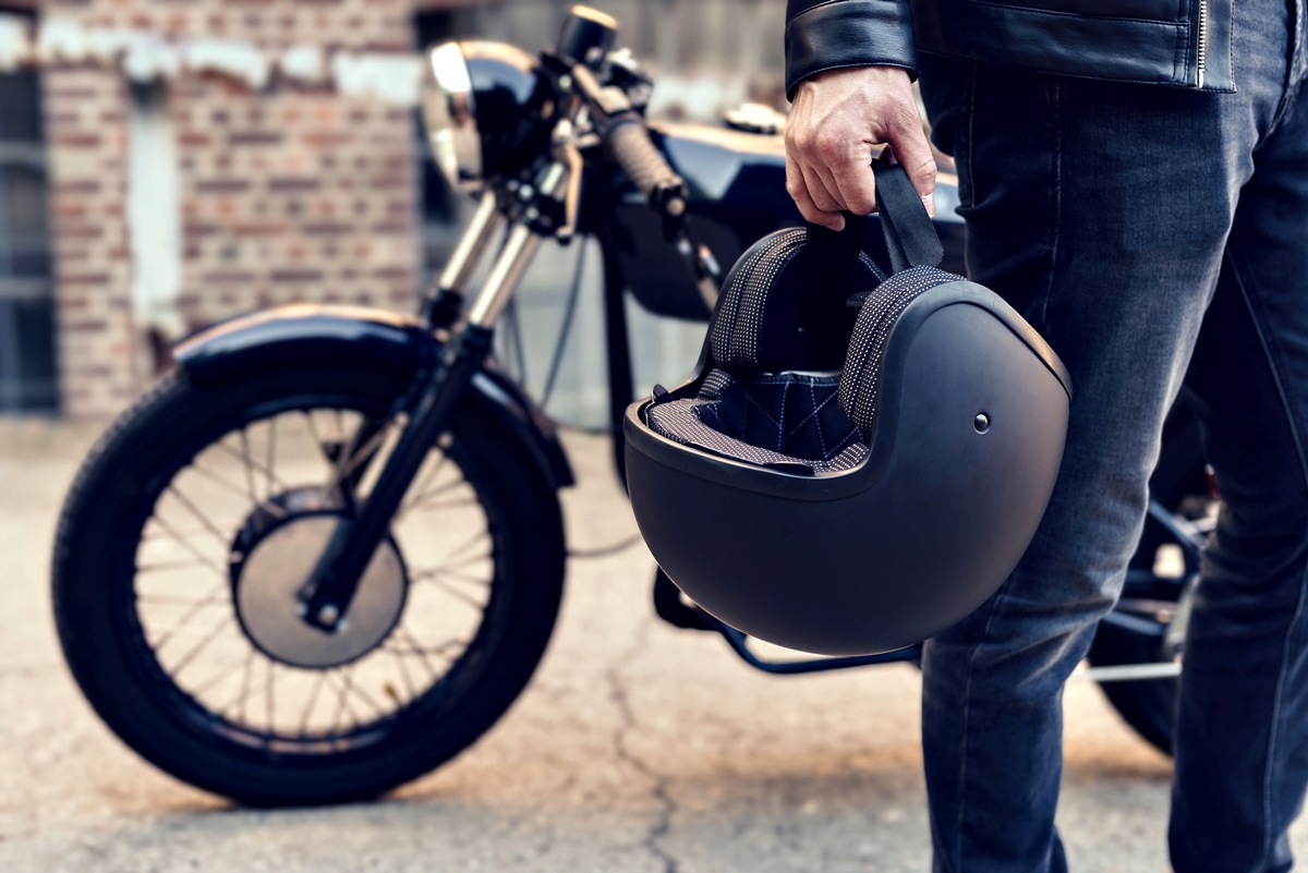 A motorcyclist holds a helmet beside a parked motorcycle in Ocala. Local police are increasing traffic enforcement through September to improve motorcycle safety.
