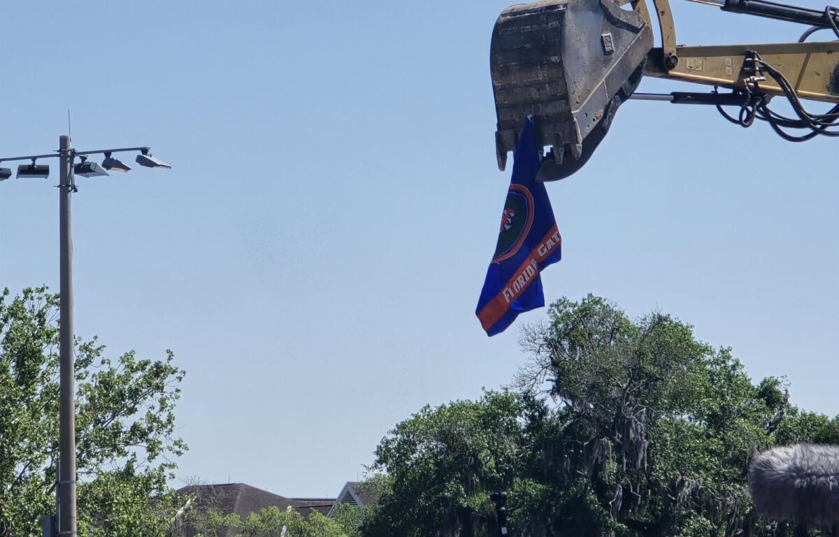 A nearby excavator holds up a Florida Gators flag near the rally.