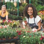 A vendor smiles while arranging plants at a flower market, one of many garden-themed displays expected at Ocala’s Big Bloom Home & Garden Show.