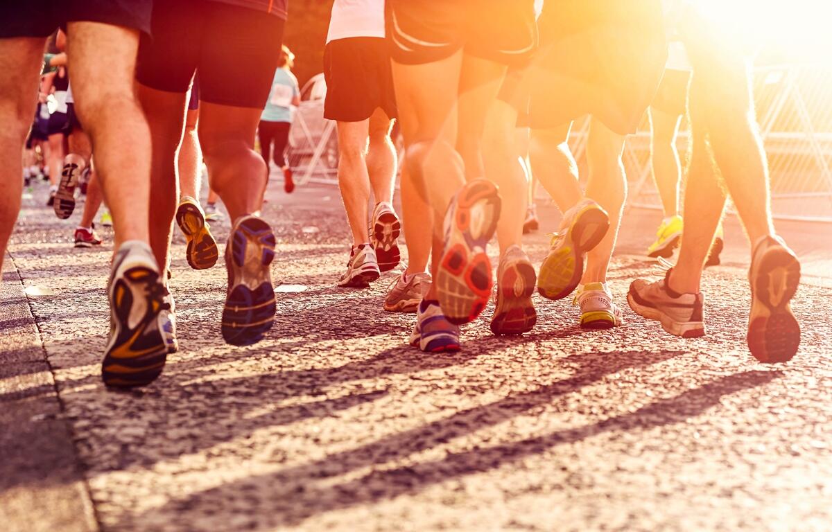Runners take off during a community 5K race, with the warm evening sun casting long shadows on the course.