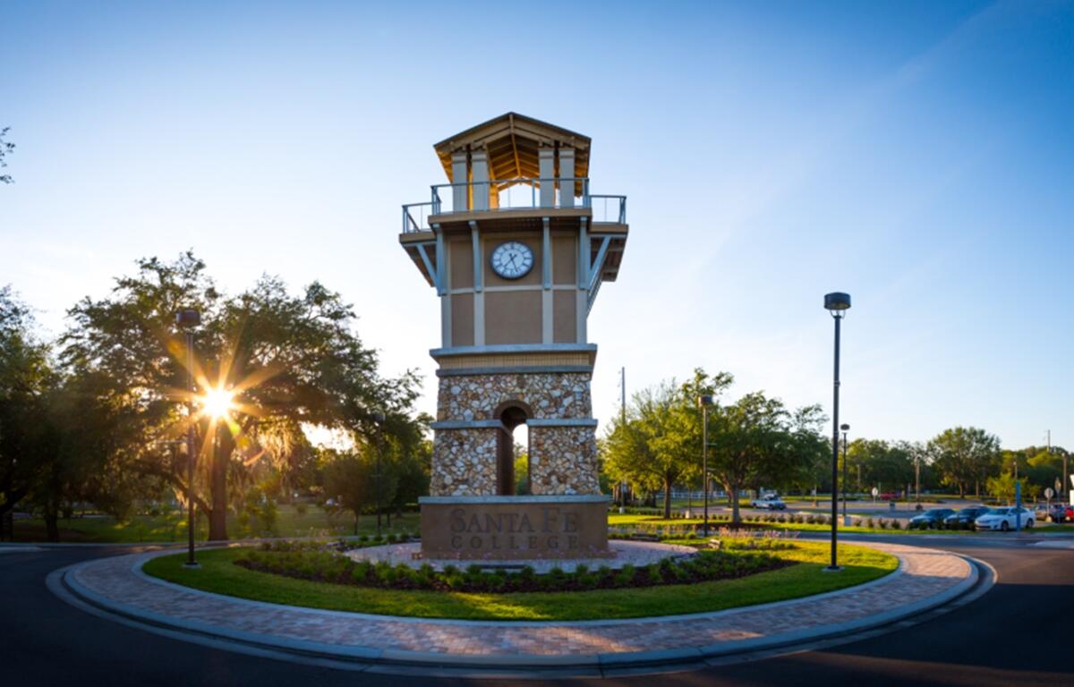 The Santa Fe College clock tower stands at the center of campus in Gainesville, FL, as the sun rises behind it.